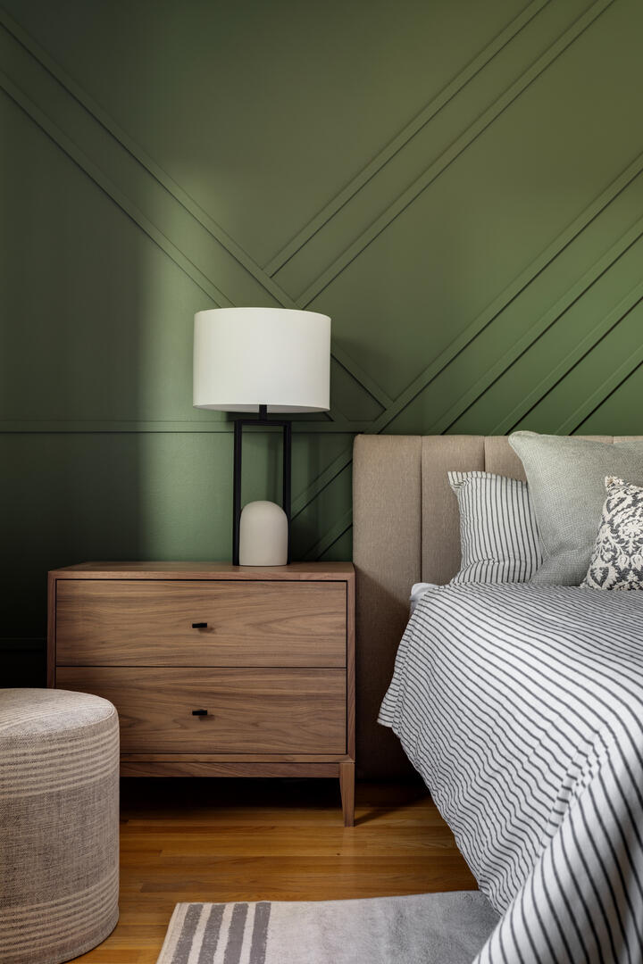Modern bedroom detail shot with green accent wall, transitional primary bedroom with wood furniture and neutral decor