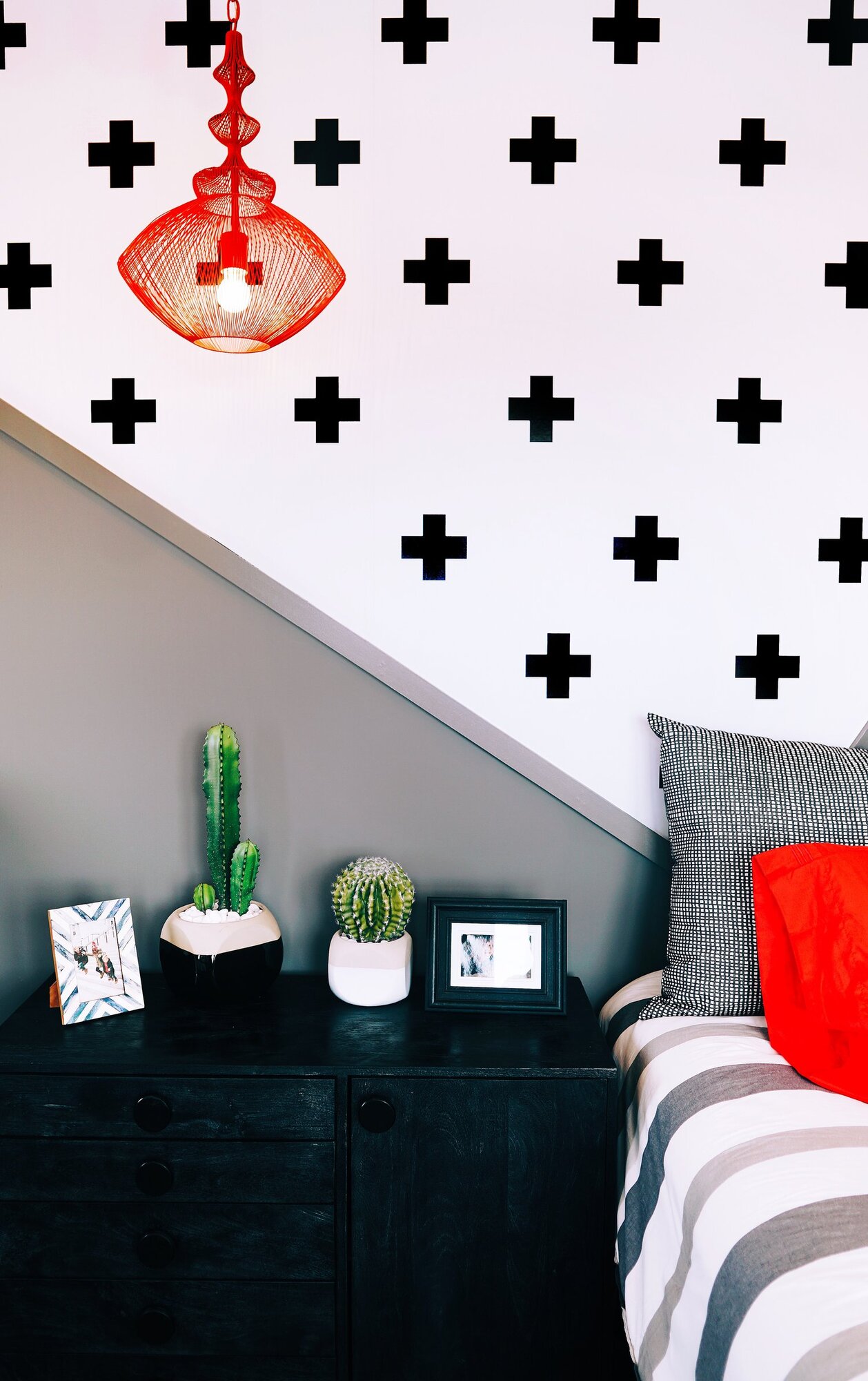 Red wire pendant light in front of bold pattern wallpaper