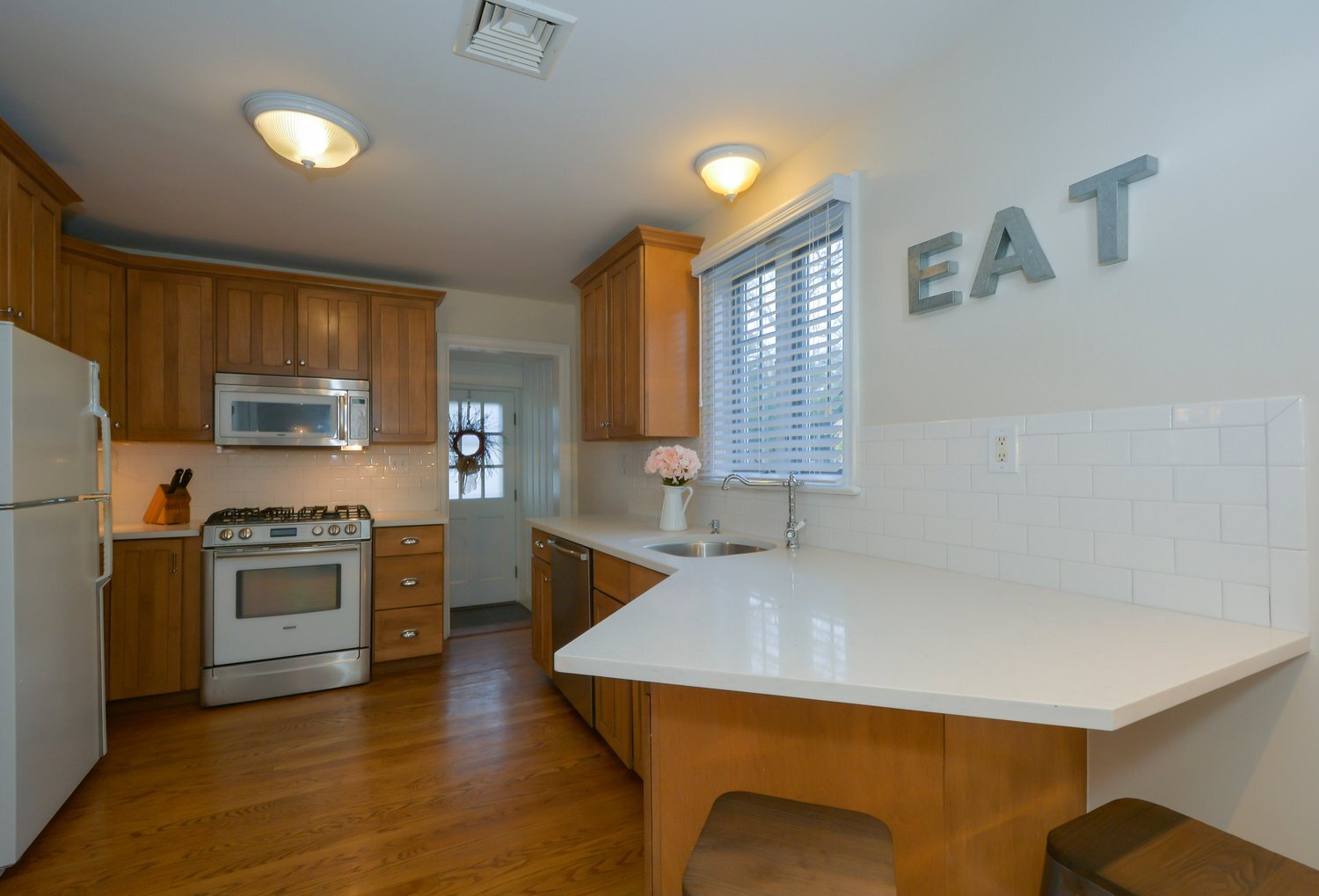 A kitchen with orange cabinets and white countertops and stainless steel appliances