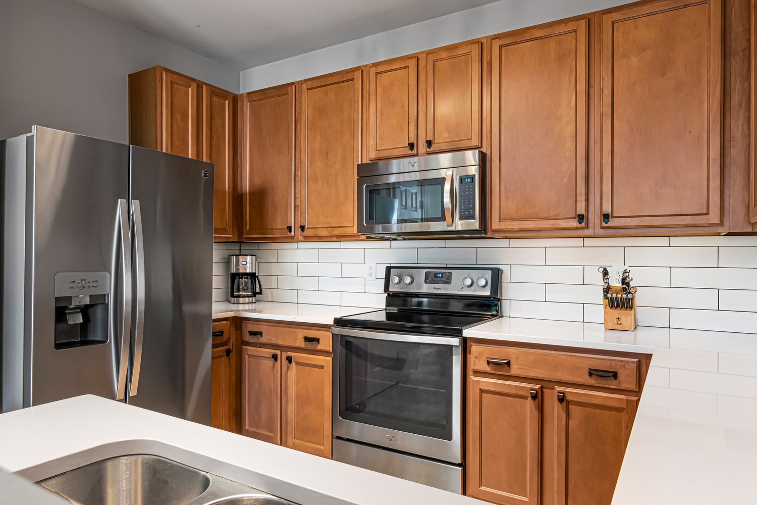 A kitchen with oak orange cabinets and white countertops