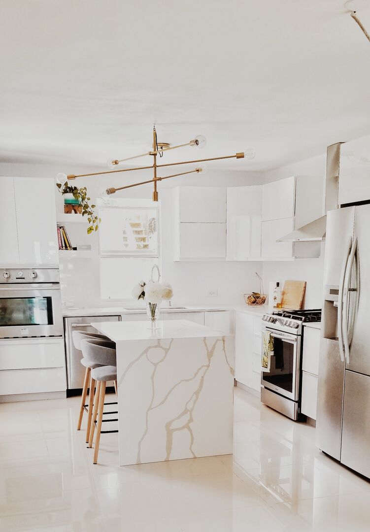 A bright white and gold modern kitchen with many plants